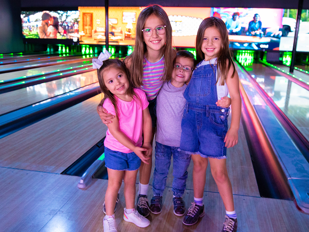 a group of young kids smiling and bowling together